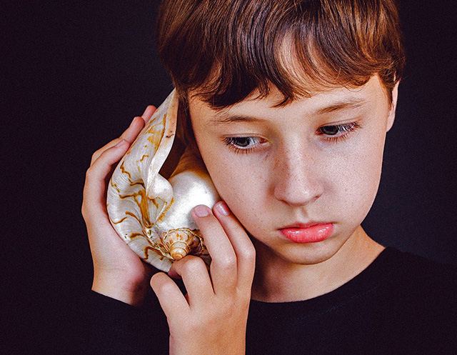 child listening to a shell